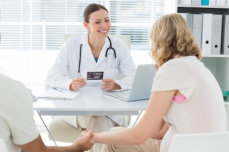 Happy female gynaecologist talking to expectant couple in clinic Photographie de stock - Aubaine LD & Abonnement, Code: 400-07473275