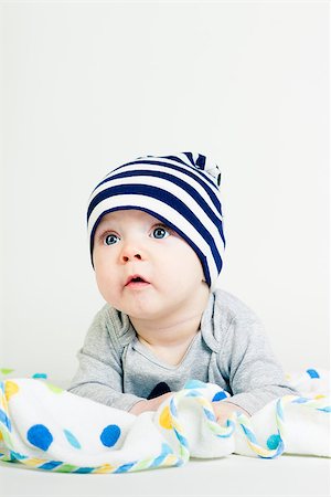 pzromashka (artist) - Portrait of a cute baby in striped hat lying down on a blanket Foto de stock - Super Valor sin royalties y Suscripción, Código: 400-07506230