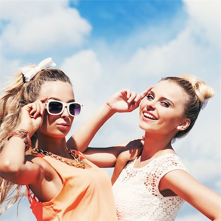 fashion face hair fun - two young girls in summer outfit pose for the camera against the blue sky Stock Photo - Budget Royalty-Free & Subscription, Code: 400-07506287