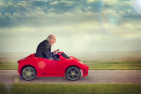 funny images of people driving - senior man enjoying driving a toy racing car Stock Photo - Budget Royalty-Free & Subscription, Code: 400-07626513