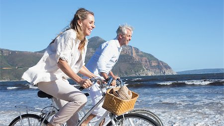 Smiling couple riding their bikes on the beach on a sunny day Stock Photo - Budget Royalty-Free & Subscription, Code: 400-07622791