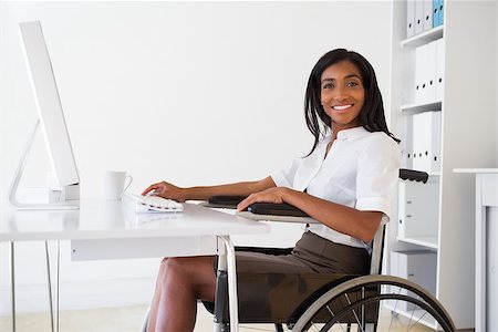 Smiling businesswoman in wheelchair working at her desk in her office Stock Photo - Budget Royalty-Free & Subscription, Code: 400-07662849