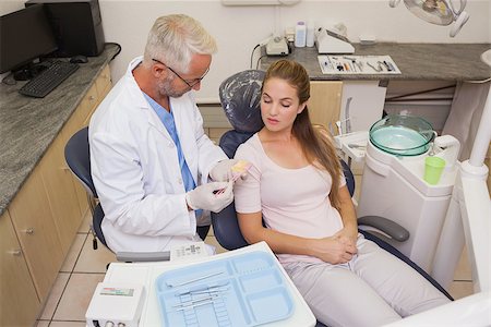 Dentist speaking with patient in the chair showing model of mouth at the dental clinic Stock Photo - Budget Royalty-Free & Subscription, Code: 400-07684793