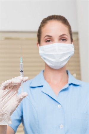 Dental assistant holding injection looking at camera at the dental clinic Stock Photo - Budget Royalty-Free & Subscription, Code: 400-07685118