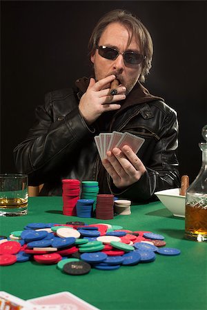 Photo of a man playing poker while wearing sunglasses and smoking a cigar. Stock Photo - Budget Royalty-Free & Subscription, Code: 400-07748292