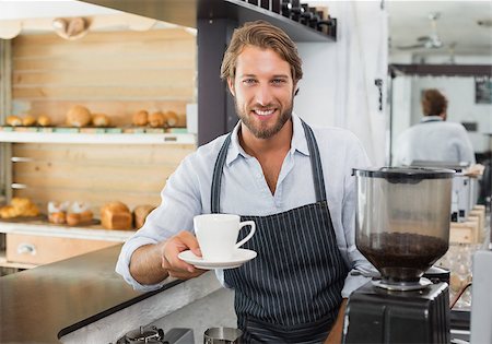 simsearch:400-07750853,k - Handsome barista offering a cup of coffee to camera at the coffee shop Stock Photo - Budget Royalty-Free & Subscription, Code: 400-07750837