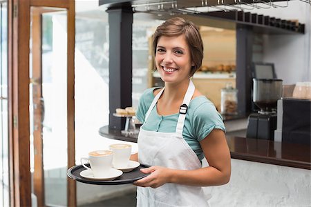 simsearch:400-07750853,k - Pretty barista smiling at camera holding tray at the coffee shop Stock Photo - Budget Royalty-Free & Subscription, Code: 400-07750847