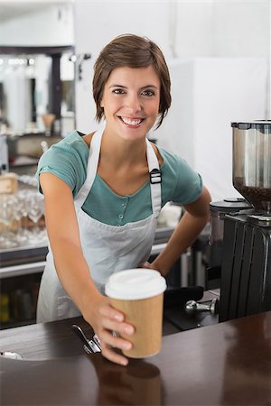 simsearch:400-07750853,k - Pretty barista smiling at camera holding disposable cup at the coffee shop Stock Photo - Budget Royalty-Free & Subscription, Code: 400-07750857