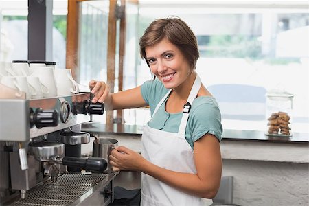 simsearch:400-07750853,k - Pretty barista steaming jug of milk at coffee machine at the coffee shop Stock Photo - Budget Royalty-Free & Subscription, Code: 400-07750868