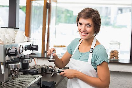 simsearch:400-07750853,k - Pretty barista pressing coffee grinds at the coffee shop Stock Photo - Budget Royalty-Free & Subscription, Code: 400-07750874