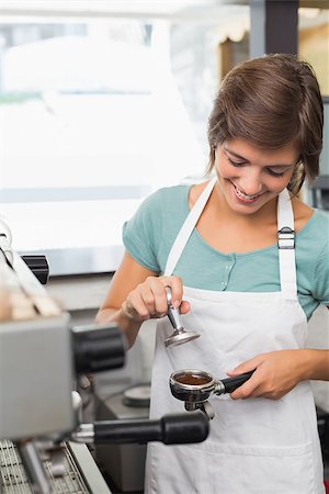 simsearch:400-07750853,k - Pretty barista pressing coffee grinds at the coffee shop Stock Photo - Budget Royalty-Free & Subscription, Code: 400-07750875