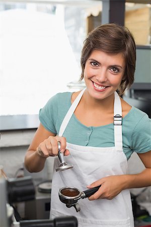 simsearch:400-07750853,k - Pretty barista pressing coffee grinds at the coffee shop Stock Photo - Budget Royalty-Free & Subscription, Code: 400-07750876