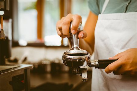 simsearch:400-07750853,k - Barista pressing fresh coffee grinds at the coffee shop Stock Photo - Budget Royalty-Free & Subscription, Code: 400-07750877