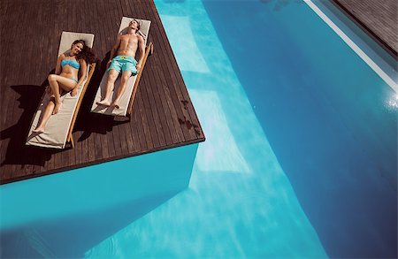 Full length of a young couple resting on sun loungers by swimming pool Stock Photo - Budget Royalty-Free & Subscription, Code: 400-07777392