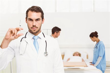 Male doctor holding injection with colleagues and patient behind Stock Photo - Budget Royalty-Free & Subscription, Code: 400-07778187