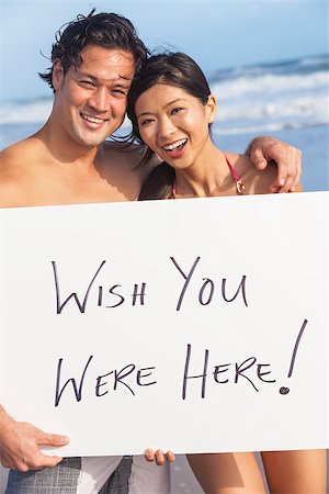 simsearch:400-07516179,k - Man & woman Asian couple, boyfriend and girlfriend in bikini, on vacation beach holding Wish You Were Here sign Stock Photo - Budget Royalty-Free & Subscription, Code: 400-07817857