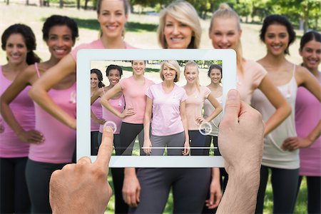 Composite image of hand holding tablet pc showing photograph of breast cancer activists Foto de stock - Super Valor sin royalties y Suscripción, Código: 400-07834665