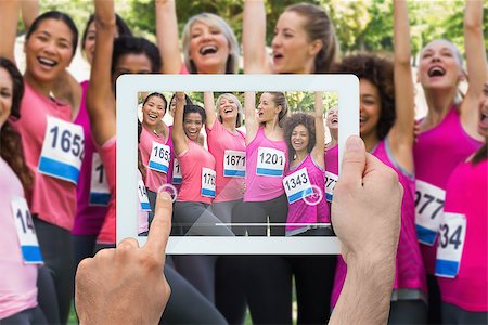 Composite image of hand holding tablet pc showing photograph of breast cancer activists Stock Photo - Budget Royalty-Free & Subscription, Code: 400-07834666