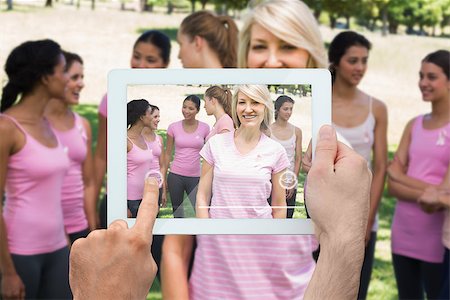 Composite image of hand holding tablet pc showing photograph of breast cancer activists Stock Photo - Budget Royalty-Free & Subscription, Code: 400-07834667