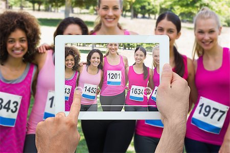 Composite image of hand holding tablet pc showing photograph of breast cancer activists Stock Photo - Budget Royalty-Free & Subscription, Code: 400-07834681