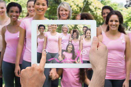 Composite image of hand holding device showing photograph of breast cancer activists Stock Photo - Budget Royalty-Free & Subscription, Code: 400-07834690