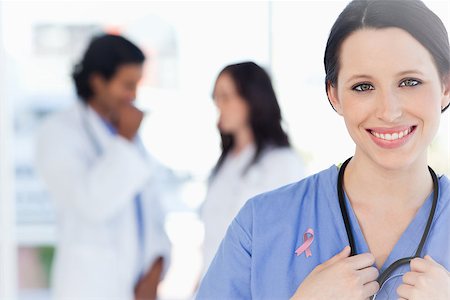 Confident nurse standing wearing breast cancer awareness ribbon Stock Photo - Budget Royalty-Free & Subscription, Code: 400-07835164