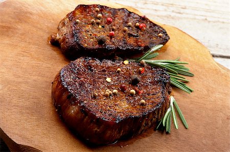 simsearch:649-06352937,k - Delicious Roasted Beef Steaks with Spices and Rosemary on Wooden Plate on Rustic Wooden background Stock Photo - Budget Royalty-Free & Subscription, Code: 400-07895275