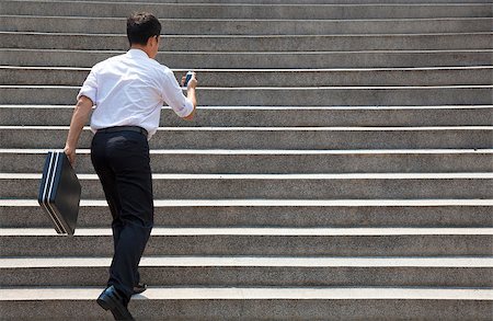 businessman holding mobile and in hurry to run up on stairs Stock Photo - Budget Royalty-Free & Subscription, Code: 400-07891895