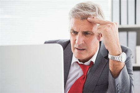 Confused businessman looking at his laptop in his office Stock Photo - Budget Royalty-Free & Subscription, Code: 400-07927892