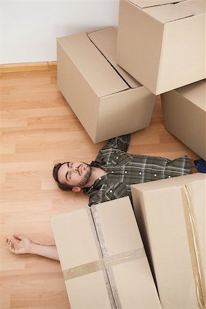 simsearch:400-07927836,k - Man lying under fallen boxes at home in the living room Stock Photo - Budget Royalty-Free & Subscription, Code: 400-07928010