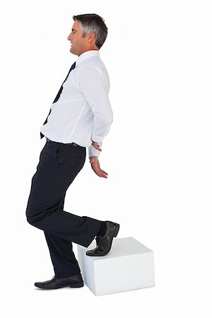 Businessman with one foot on cube and hands behind his back on white background Stock Photo - Budget Royalty-Free & Subscription, Code: 400-07930461