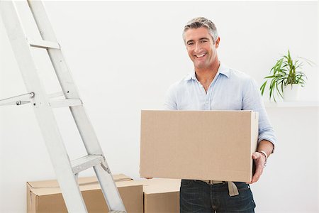 simsearch:400-07927836,k - Smiling man holding cardboard box next a stepladder at apartment Stock Photo - Budget Royalty-Free & Subscription, Code: 400-07930722