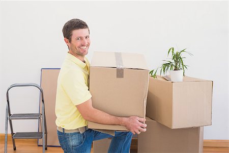 simsearch:400-07930718,k - Smiling man carrying cardboard moving boxes at home in the living room Stock Photo - Budget Royalty-Free & Subscription, Code: 400-07931101