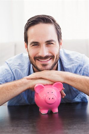 piggy - Smiling man laying on the piggy bank in the living room Stock Photo - Budget Royalty-Free & Subscription, Code: 400-07931298