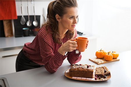 Happy young housewife drinking tea with freshly baked pumpkin bread with seeds in kitchen Stock Photo - Budget Royalty-Free & Subscription, Code: 400-07956860