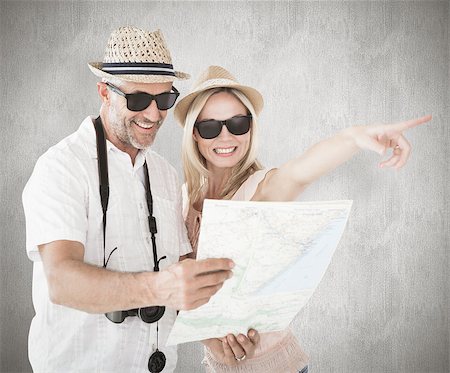 simsearch:400-07957355,k - Happy tourist couple using map and pointing against weathered surface Stock Photo - Budget Royalty-Free & Subscription, Code: 400-07957392