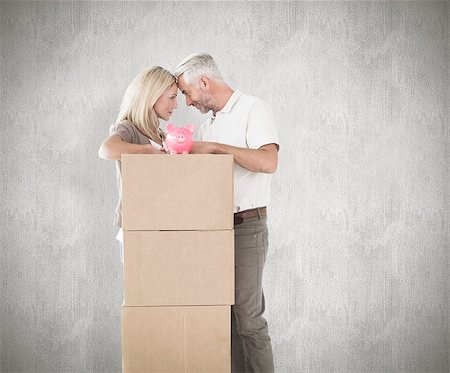 simsearch:400-07957420,k - Happy couple leaning on pile of moving boxes with piggy bank against weathered surface Photographie de stock - Aubaine LD & Abonnement, Code: 400-07957403
