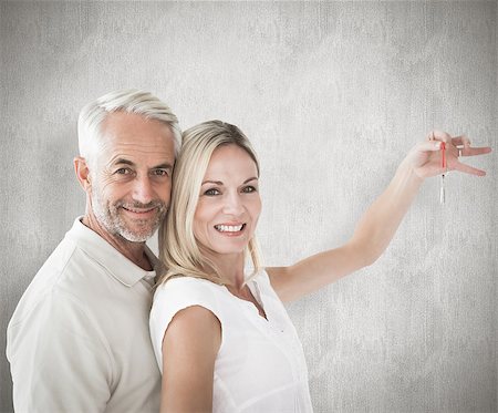 simsearch:400-07957355,k - Happy couple showing their new house key against weathered surface Stock Photo - Budget Royalty-Free & Subscription, Code: 400-07957410