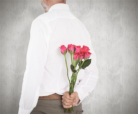 simsearch:400-07957420,k - Man holding bouquet of roses behind back against weathered surface Photographie de stock - Aubaine LD & Abonnement, Code: 400-07957413