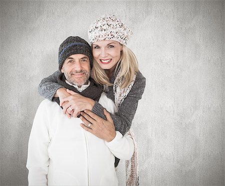 simsearch:400-07957420,k - Happy couple in winter fashion embracing against weathered surface Photographie de stock - Aubaine LD & Abonnement, Code: 400-07957426