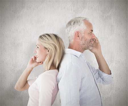 simsearch:400-07957355,k - Happy couple talking on their smartphones against weathered surface Stock Photo - Budget Royalty-Free & Subscription, Code: 400-07957445