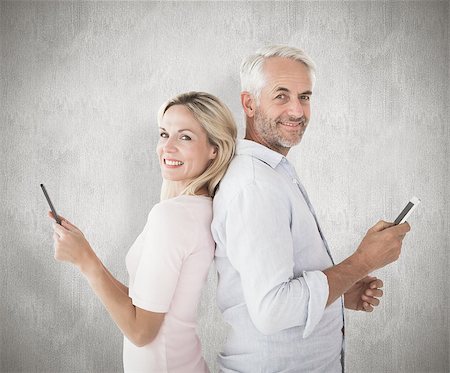 simsearch:400-07957355,k - Happy couple texting on their smartphones against weathered surface Stock Photo - Budget Royalty-Free & Subscription, Code: 400-07957446