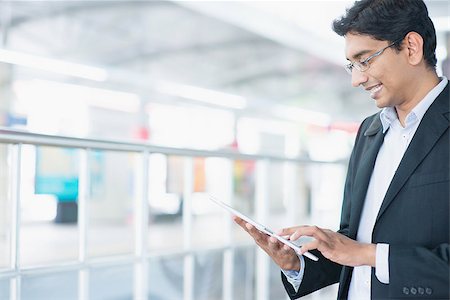 Asian Indian businessman using tablet pc while waiting train at railway station. Stock Photo - Budget Royalty-Free & Subscription, Code: 400-07978374