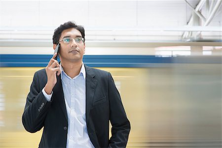 Asian Indian businessman on the phone while waiting train at railway station. Stock Photo - Budget Royalty-Free & Subscription, Code: 400-07978370