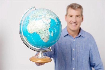 Smiling mature man showing globe to camera Stock Photo - Budget Royalty-Free & Subscription, Code: 400-07984829