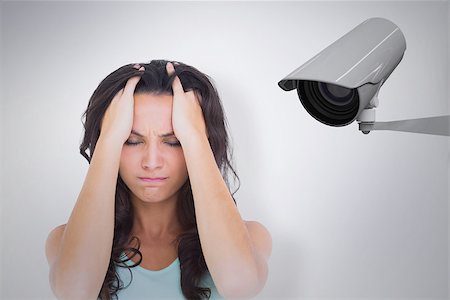 Pretty brunette with a headache against cctv camera Stock Photo - Budget Royalty-Free & Subscription, Code: 400-08019214