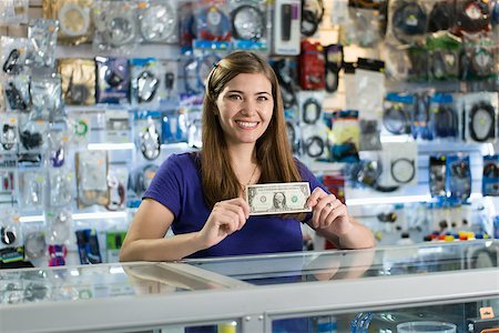 diego_cervo (artist) - Young white woman working as shop owner in computer store, showing her first dollar to the camera and smiling. Rack focus from woman's face to banknote Stock Photo - Budget Royalty-Free & Subscription, Code: 400-08049529