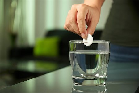 diego_cervo (artist) - Closeup of effervescen tablet aspirin in glass of water, with sick young woman laying and relaxing on sofa in background Stock Photo - Budget Royalty-Free & Subscription, Code: 400-08052235