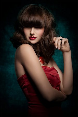 Pretty, mysterious, gorgeous woman with smooth brown hair with straight fringe wearing red, satin top, big old necklace and red lipstick, her eyes are in shadow. Stock Photo - Budget Royalty-Free & Subscription, Code: 400-08052409