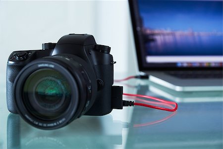 diego_cervo (artist) - Still life of dslr camera connected with USB cable to laptop computer on glass table. The photo camera is transferring images to PC in background. Copy space Stock Photo - Budget Royalty-Free & Subscription, Code: 400-08077777
